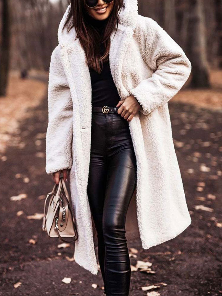 Frau in weißem Teddy-Mantel, schwarze Lederhose, Sonnenbrille, Herbstwald. Modetrend, stilvoll, elegant, Damenmode, Herbstoutfit.