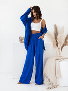 Frau in blauer Leinenhose und passender Jacke, weißem Top. Modetrend, Sommeroutfit, lässiger Stil, Damenbekleidung, elegantes Design.