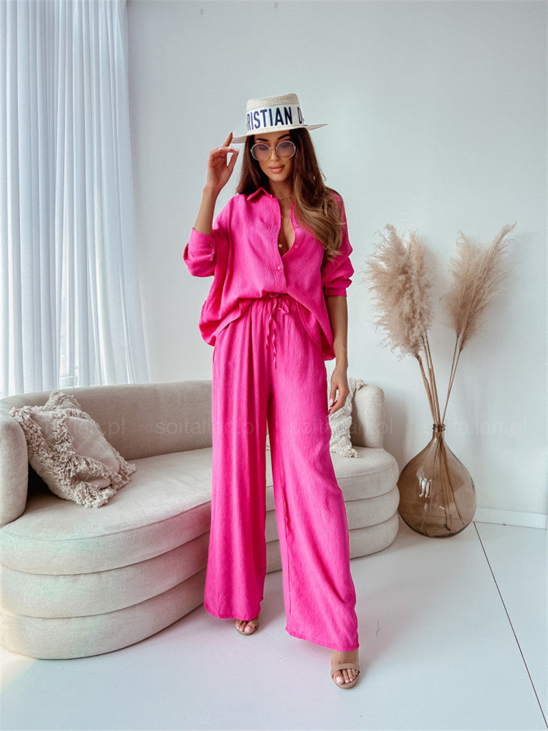 Frau in pinkem Leinenanzug posiert stilvoll im modernen Wohnzimmer. Trendige Mode, Sommeroutfit, elegantes Design, Damenbekleidung.