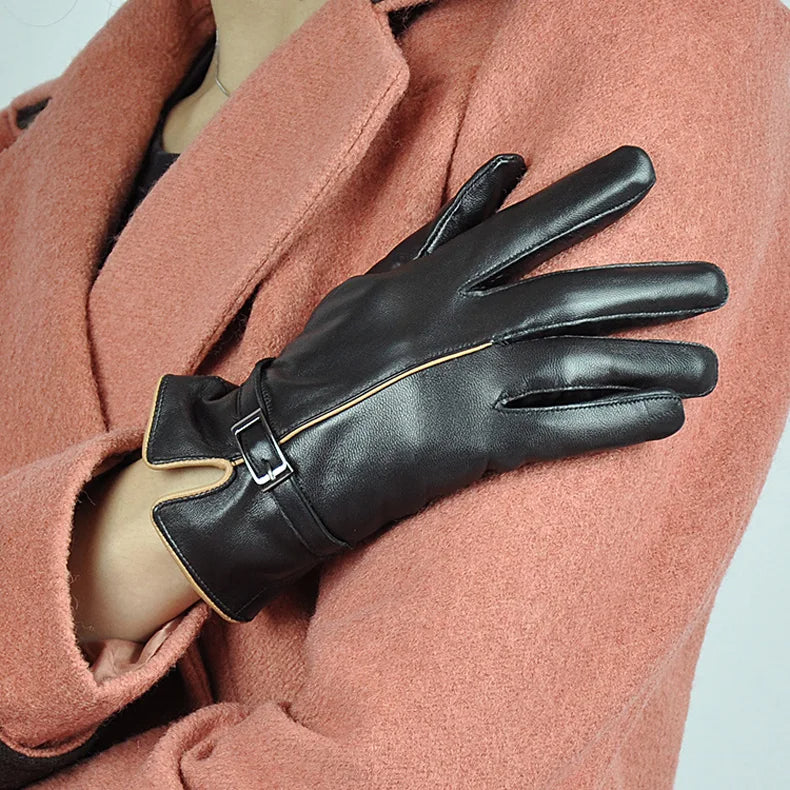 Damenhandschuhe aus schwarzem Leder mit Schnalle, getragen zu rosa Mantel.