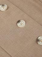 Beige Blazerstoff mit Perlmuttknöpfen, elegantes Design, hochwertige Mode, Detailansicht.