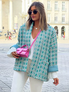 Frau in stilvoller, gemusterter Jacke und weißem Outfit, trägt eine pinke Designer-Handtasche. Perfekt für Mode, Streetstyle, urbane Trends.