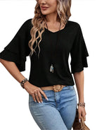 Frau in schwarzem Rüschen-Top und blauer Jeans, modisches Outfit, lässiger Stil.