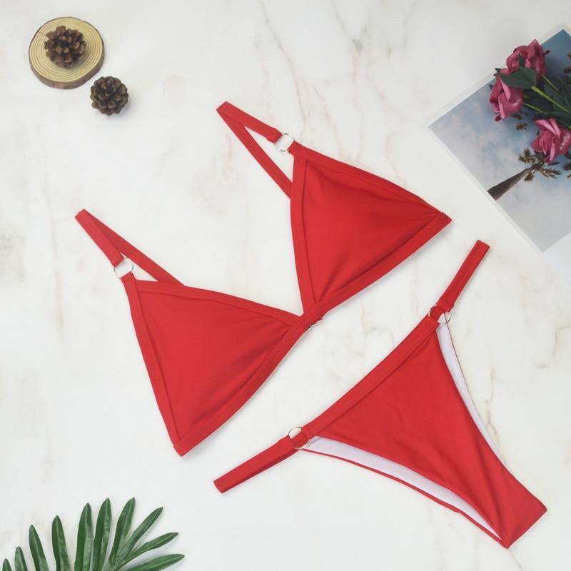 Rotes Bikini-Set auf Marmorhintergrund, zweiteilig, ideal für Sommer und Strand. Modisches Design, hochwertige Bademode für Damen.
