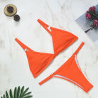 Zweifarbiger Bikini in leuchtendem Orange auf Marmorhintergrund, ideal für Sommermode und Strandbekleidung. Perfekt für stilvolle Badebekleidung.