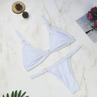 Weißes Bikini-Set auf Marmorhintergrund, ideal für Sommermode. Zweiteiliger Badeanzug, stilvoll und modern. Perfekt für Strandurlaub.
