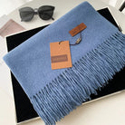 Luxuriöses, blaues Kaschmirschal mit Fransen von Gerunsi, ideal für stilvolle Wintermode. Perfekt als Geschenk oder modisches Accessoire.