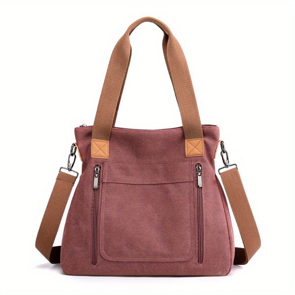 Damenhandtasche aus rosa Canvas mit braunen Trägern, Reißverschlusstaschen und abnehmbarem Schultergurt. Modisch, praktisch, vielseitig.