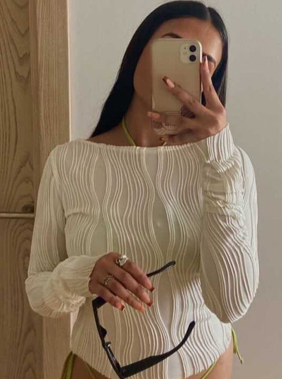 Frau in weißem, geripptem Langarmshirt macht Selfie mit Smartphone, hält Sonnenbrille. Modetrend, Damenmode, Selfie, Accessoires.