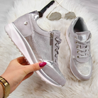 Damen Sneaker in Silber mit Glitzer, Reißverschluss und Schnürung auf weißem Fellhintergrund. Modische, bequeme Schuhe für Alltag und Freizeit.