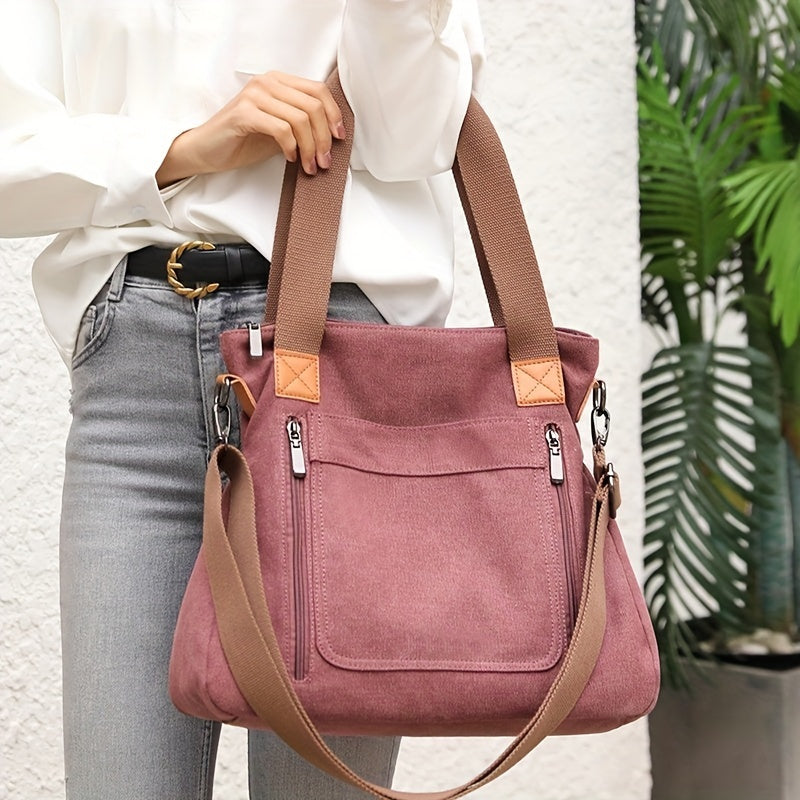Damenhandtasche aus rosa Canvas mit braunen Trägern, Reißverschlusstaschen und verstellbarem Schultergurt. Modisch, praktisch, vielseitig.