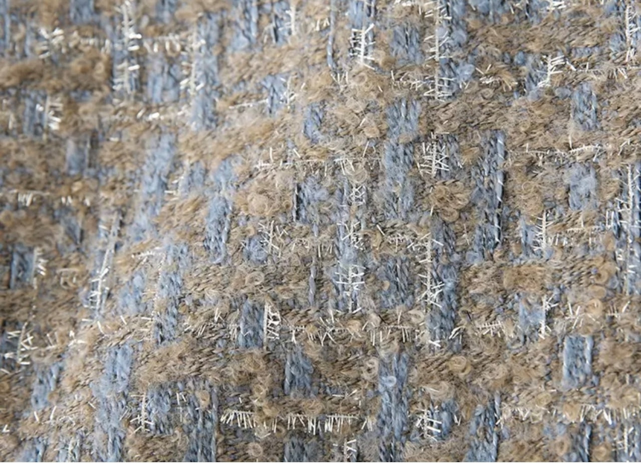 Nahaufnahme von strukturiertem Tweed-Stoff in Beige und Blau, ideal für Mode und Inneneinrichtung. Hochwertiger Textilstoff, elegant und vielseitig.