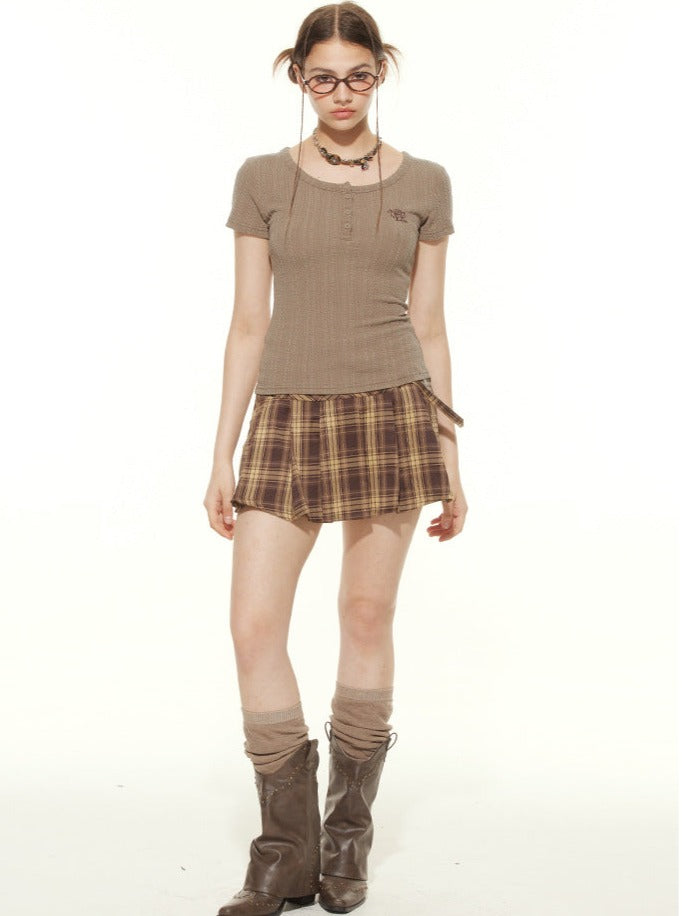 Junge Frau im modischen, karierten Minirock, braunem Oberteil und Stiefeln. Trendige Herbstmode, lässiger Look, Streetwear-Style.