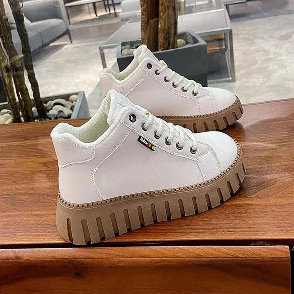 Weiße Sneaker mit dicker, geriffelter Sohle auf Holztisch. Modische, bequeme Schuhe für Damen und Herren. Ideal für Freizeit und Alltag.