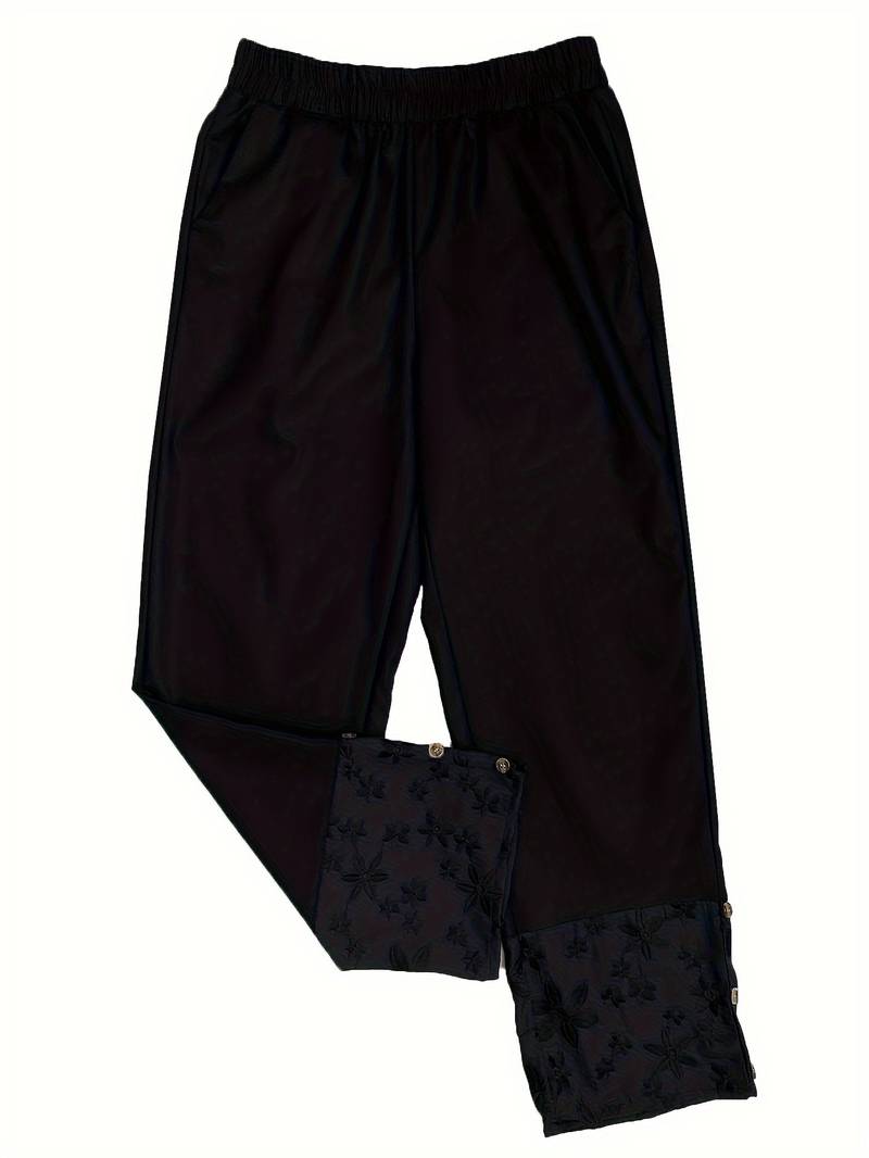 Schwarze Damenhose mit elastischem Bund und floraler Stickerei am Saum, ideal für Freizeit und Büro. Bequeme Passform, modisches Design.