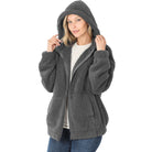 Frau in grauer Fleecejacke mit Kapuze, Reißverschluss, lässig, warm, modisch, Herbstbekleidung.