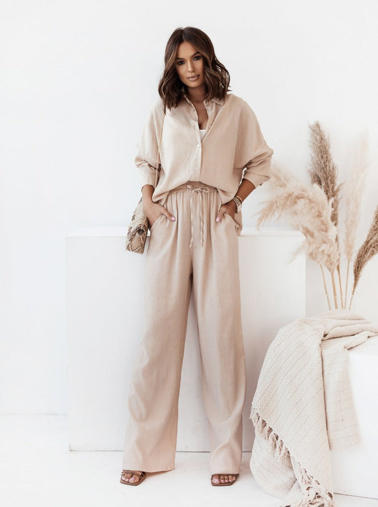 Elegantes Damen-Outfit in Beige: Weite Hose und lockere Bluse aus Leinen, ideal für Sommermode. Perfekt kombiniert mit Sandalen und Strohtasche.