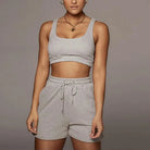 Graues Sportset für Damen, bestehend aus kurzem Top und Shorts. Ideal für Fitness und Freizeit. Bequemes Material, modisches Design.