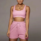 Rosa Sportset für Damen, bestehend aus kurzem Top und Shorts. Ideal für Fitness und Freizeit. Bequemes Material, modisches Design.