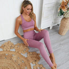 Frau in rosa Sportset, klassischer Schnitt, sitzt auf Holzboden. Perfekt für Yoga, Fitness und Freizeit. Bequemes, stilvolles Sportoutfit.