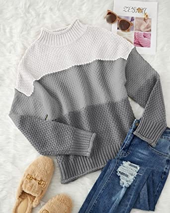 Eleganter gestreifter Pullover in Grau und Weiß, ideal für Herbstmode. Kombiniert mit zerrissenen Jeans und beigen Hausschuhen auf flauschigem Teppich.