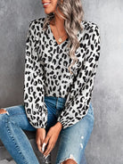 Damenbluse mit Leopardenmuster, V-Ausschnitt und langen Ärmeln, kombiniert mit zerrissenen Jeans. Modetrend, stilvoll, lässig, elegant.