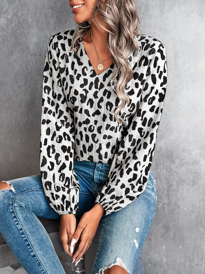 Damenbluse mit Leopardenmuster, V-Ausschnitt und langen Ärmeln, kombiniert mit zerrissenen Jeans. Modetrend, stilvoll, lässig, elegant.