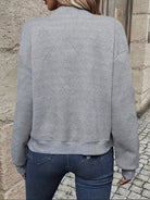 Grauer Strickpullover mit geometrischem Muster, Damenmode, lässiger Stil, ideal für Herbst und Winter, kombiniert mit blauen Jeans.