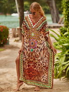 Frau im eleganten Kaftan mit Leopardenmuster und bunten Verzierungen am Strand. Sommermode, Boho-Chic, Strandkleidung, Damenmode.
