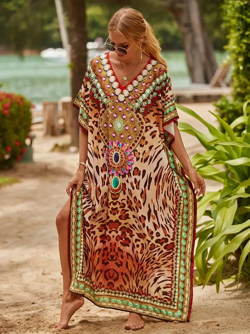 Frau im eleganten Kaftan mit Leopardenmuster und bunten Verzierungen am Strand. Sommermode, Boho-Chic, Strandkleidung, Damenmode.