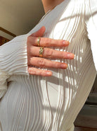 Elegantes weißes Plissee-Kleid mit goldenen Ringen, modisches Design, hochwertige Damenmode, stilvolle Textur, trendige Accessoires.