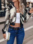 Frau trägt modische Camouflage-Bomberjacke, weiße Tasche und Jeans. Trendige Damenmode, Streetstyle, lässiger Look, stilvolle Outfits.