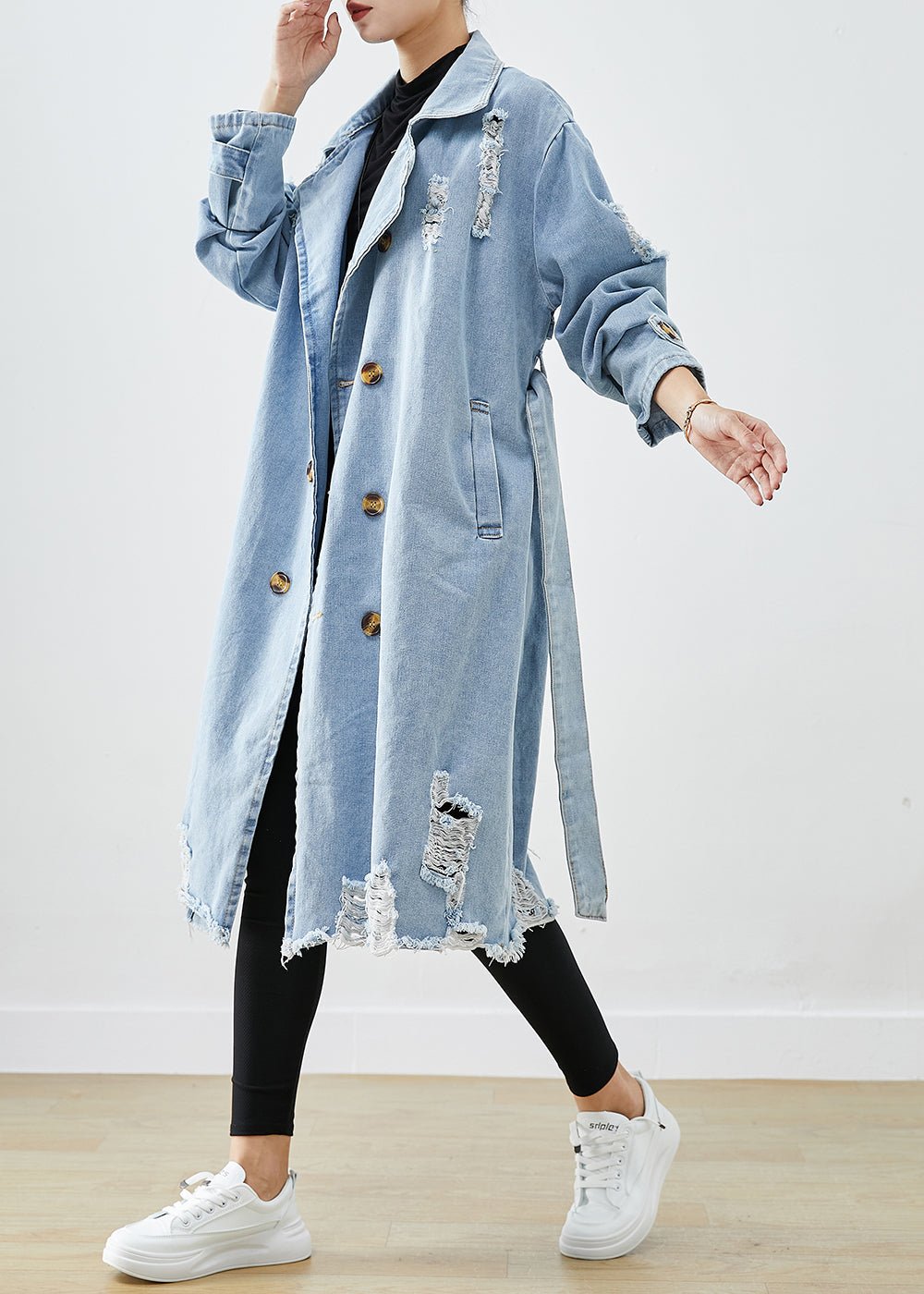 Hellblauer, zerrissener Denim-Mantel mit Revers und doppelter Knopfleiste, ideal für den Herbst. Modischer Damenmantel, lässiger Streetwear-Stil.