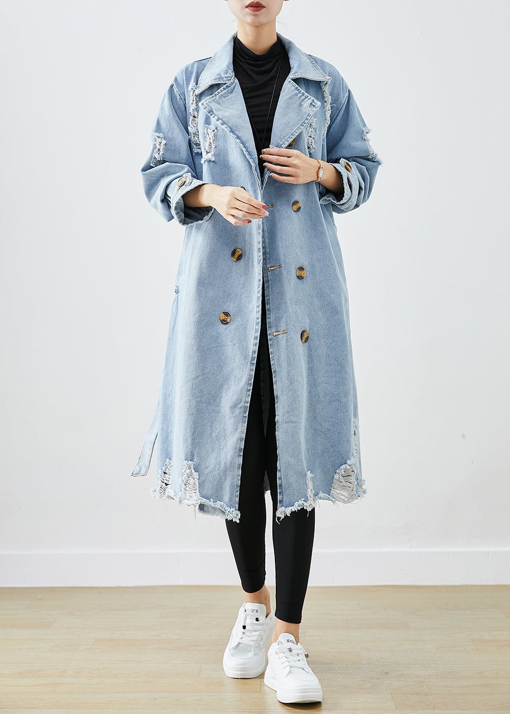 Hellblauer, zerrissener Denim-Mantel mit Revers und doppelter Knopfleiste, ideal für den Herbst. Modischer, lässiger Look für Damen.