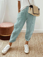 Damenhose mit grün-weißen Streifen, kombiniert mit weißem T-Shirt und Strohtasche. Perfekt für lässige Sommermode und Freizeitoutfits.