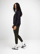 Schwarze Zip-Bluse für Damen, kombiniert mit olivgrüner Leggings. Perfekt für Sport und Freizeit. Modisch, bequem, vielseitig einsetzbar.