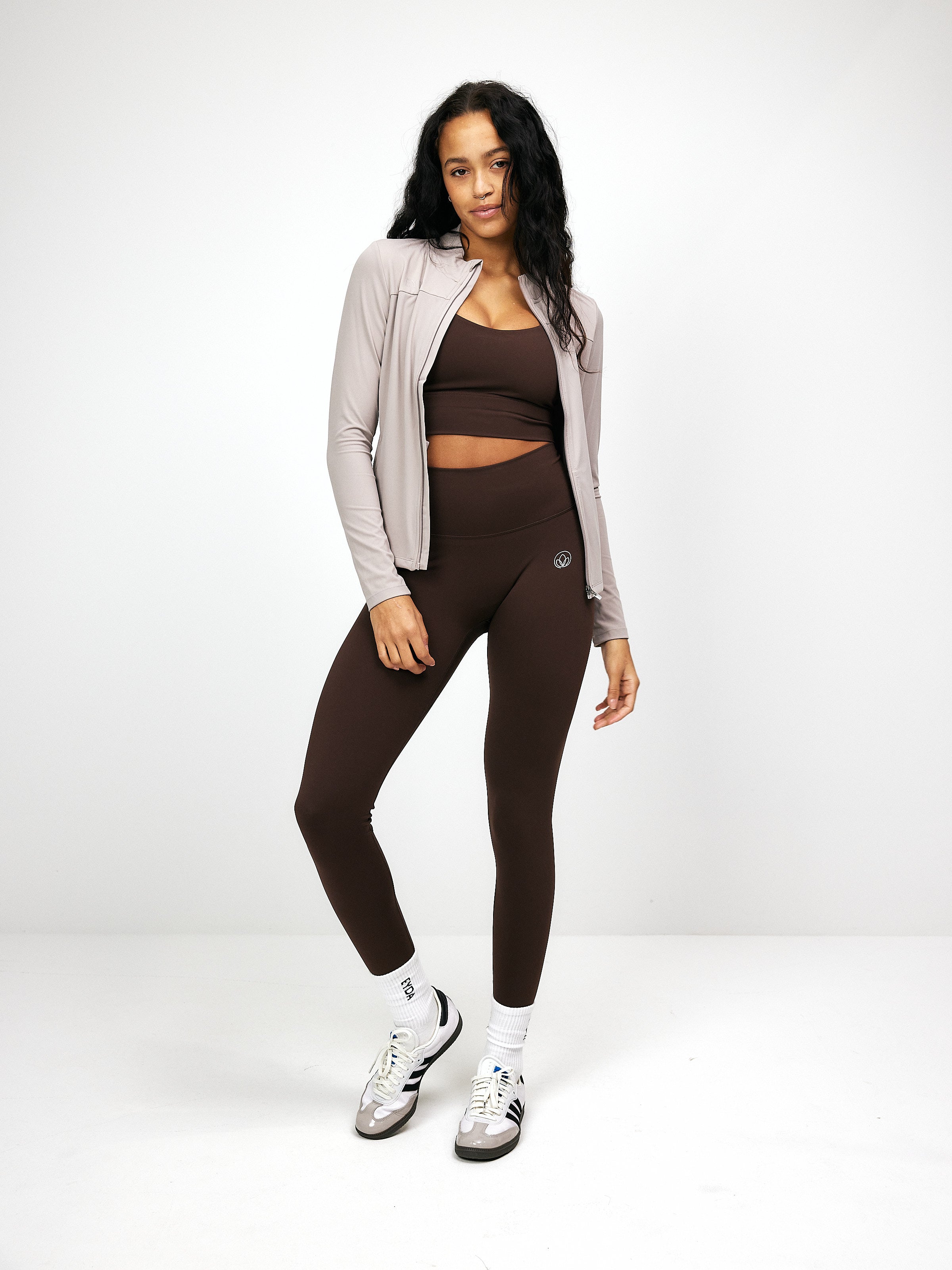 Damen-Sportoutfit: Taupefarbene Zip-Bluse und braune Leggings. Perfekt für Fitness, Yoga und Freizeit. Bequeme, stilvolle Sportbekleidung.
