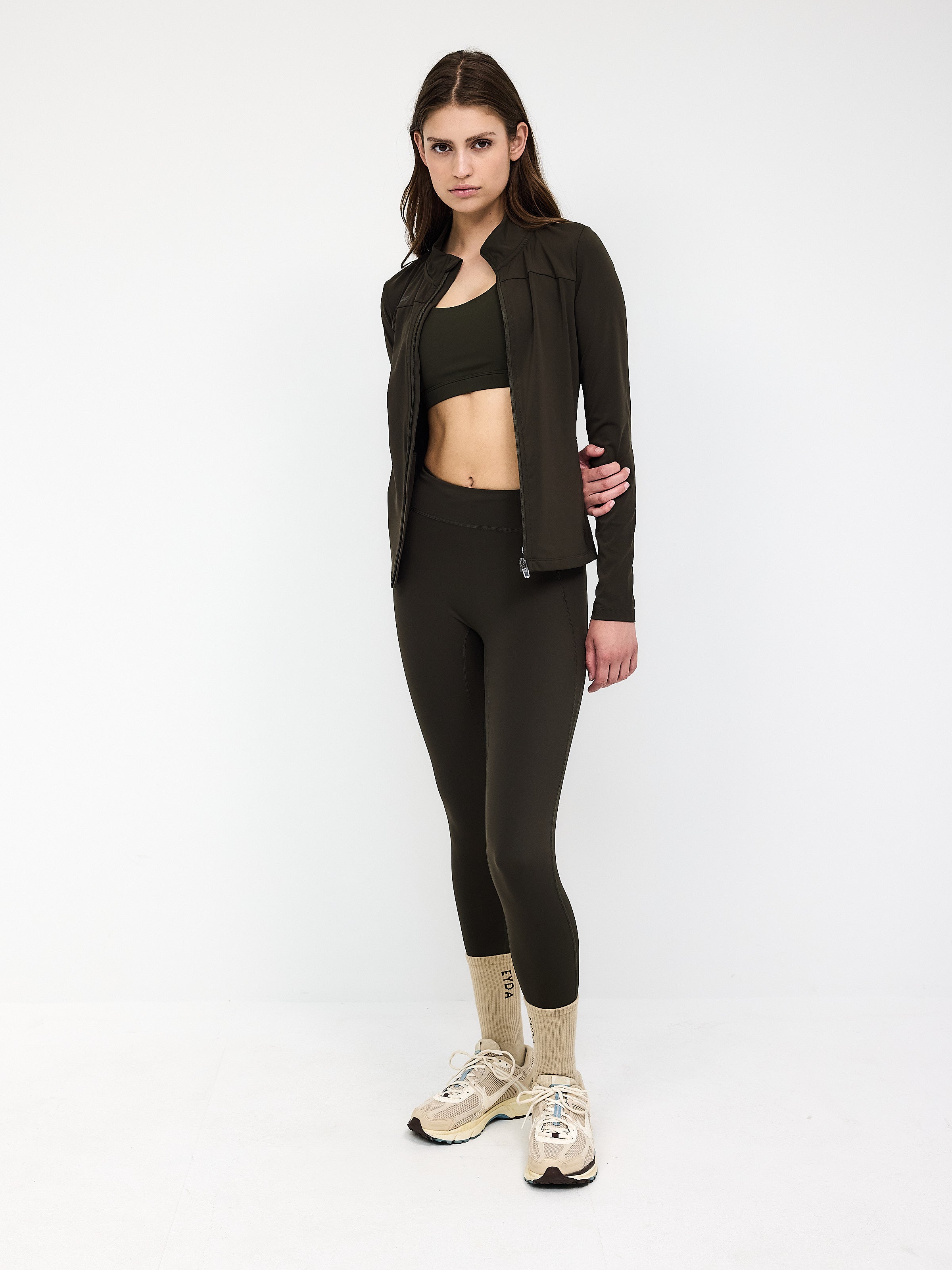 Damen-Sportoutfit in Dunkeloliv: Jacke, Sport-BH und Leggings. Perfekt für Fitness, Yoga und Freizeit. Trendige Sportmode für aktive Frauen.