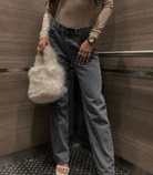 Baggy-Jeans in Grau mit zerrissenem Design, kombiniert mit beiger Bluse und flauschiger Handtasche. Trendige Damenmode, lässiger Streetstyle.