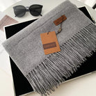 Grauer Kaschmirschal mit Fransen, stilvoll und weich, ideal für Herbst und Winter. Perfektes Accessoire für Damenmode. Hochwertige Verarbeitung.