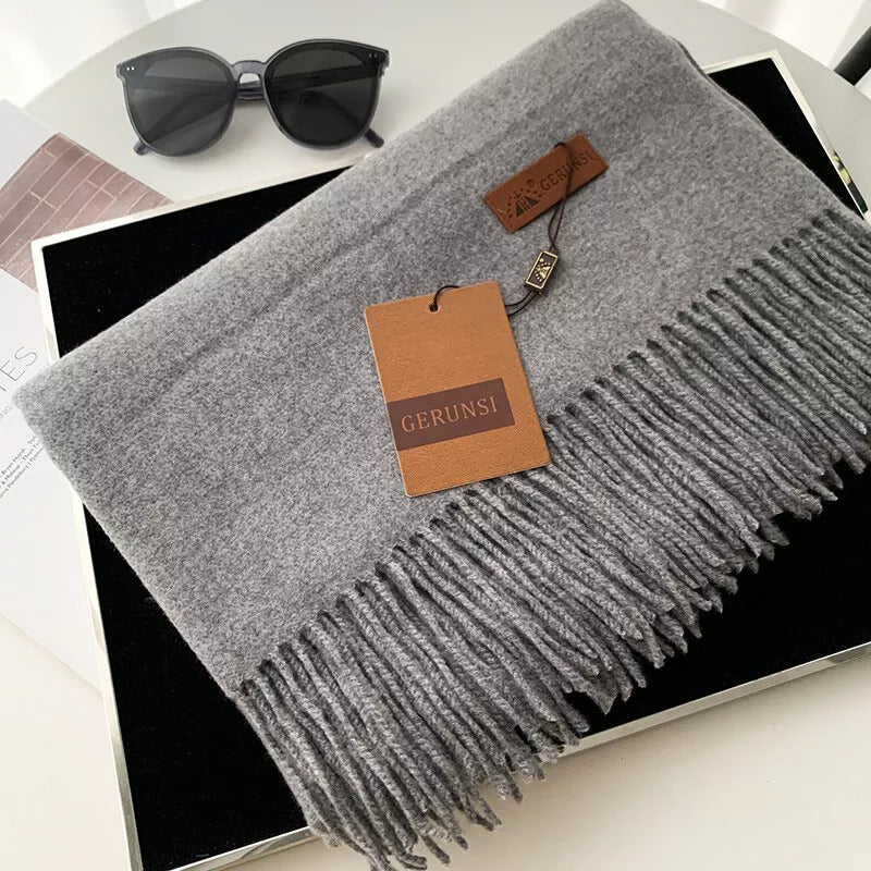 Grauer Kaschmirschal mit Fransen, stilvoll und weich, ideal für Herbst und Winter. Perfektes Accessoire für Damenmode. Hochwertige Verarbeitung.