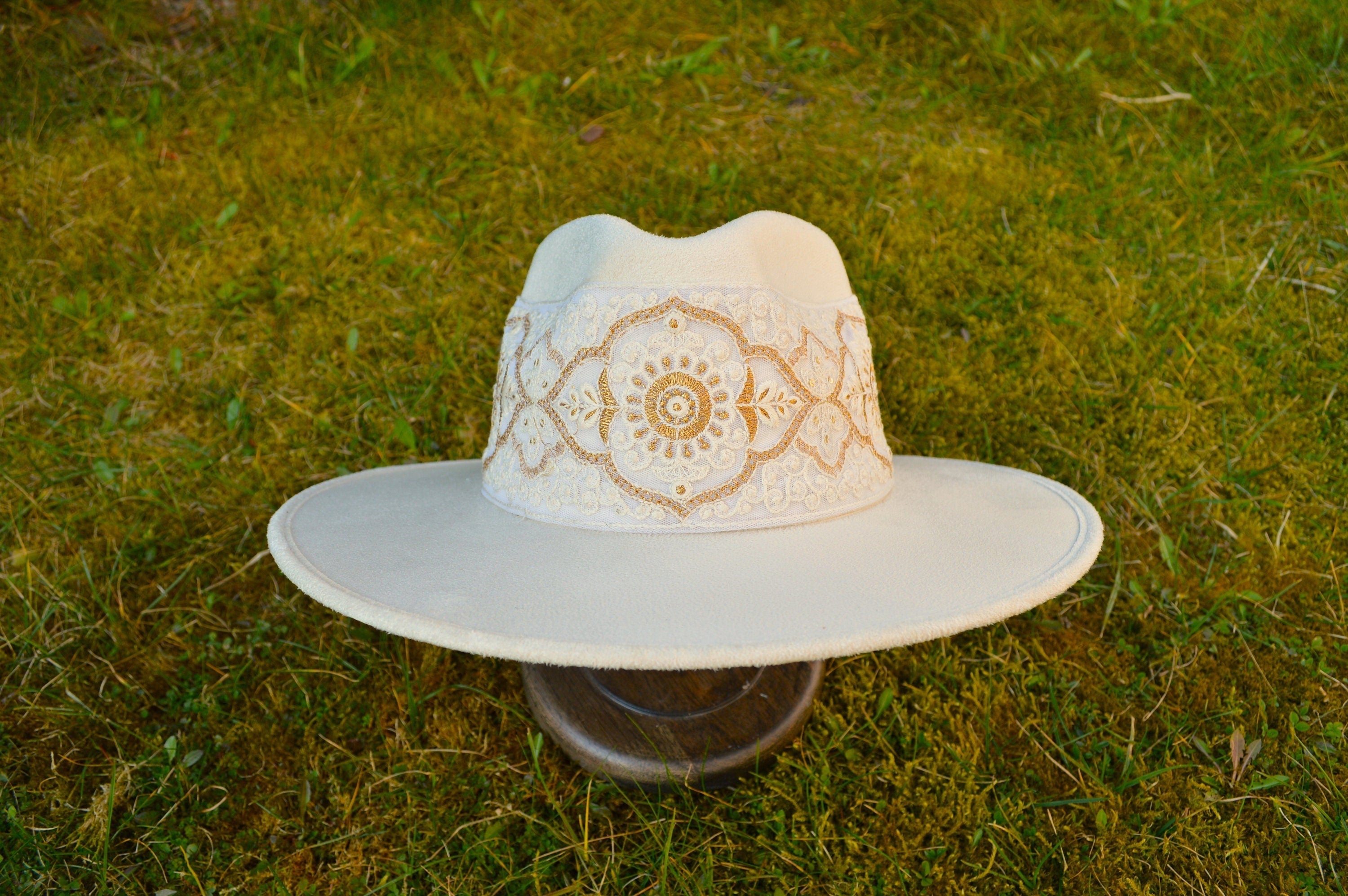 Eleganter weißer Filzhut mit breiter Krempe und kunstvoller Stickerei auf grünem Hintergrund. Perfekt für stilvolle Mode und Accessoires.