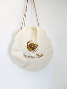 Elegante, runde Stofftasche mit "Serena Hats"-Logo, ideal für umweltfreundliches Einkaufen. Nachhaltige Mode, stilvolle Accessoires.