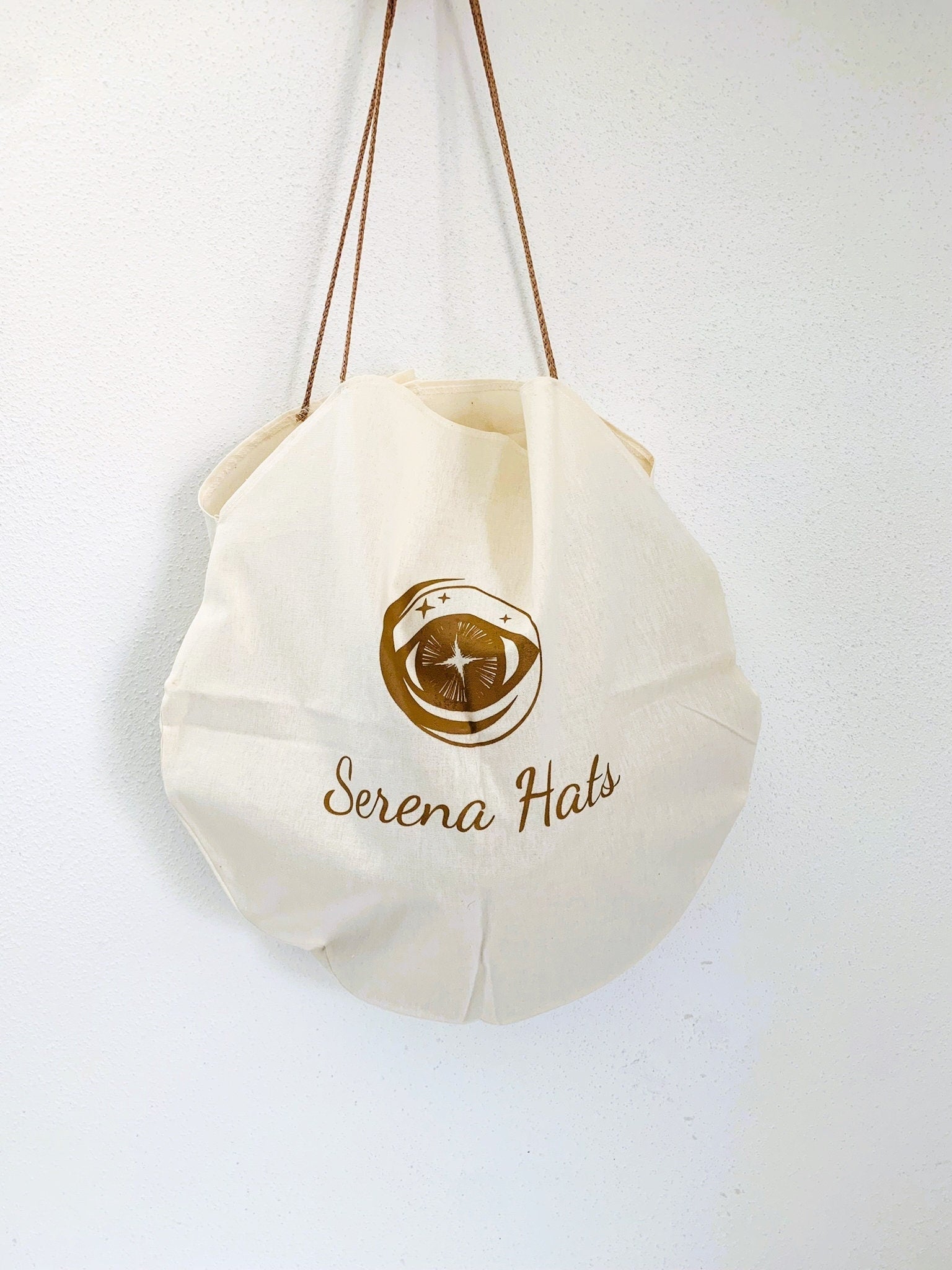 Elegante, runde Stofftasche mit "Serena Hats"-Logo, ideal für umweltfreundliches Einkaufen. Nachhaltige Mode, stilvolle Accessoires.