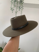 Damen-Filzhut in Olivgrün mit breiter Krempe und schwarzem Lederband, verziert mit Nieten. Trendiger Hut für Herbstmode und Outdoor-Aktivitäten.