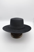 Schwarzer Filzhut mit breiter Krempe auf Holzständer, klassisches Design, ideal für stilvolle Outfits, zeitloser Modeaccessoire.