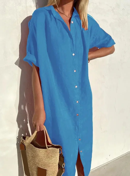 Frau in blauem Leinenkleid mit Knopfleiste, hält eine Strohtasche, Sommermode.
