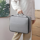 Person hält graue, tragbare Aufbewahrungstasche mit Reißverschluss, ideal für Reisen und Organisation.