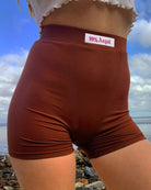 Damen-Shorts in Braun mit hohem Bund und "99% Angel"-Aufdruck, ideal für Strandmode. Bequeme Passform, perfekt für Sommeraktivitäten.