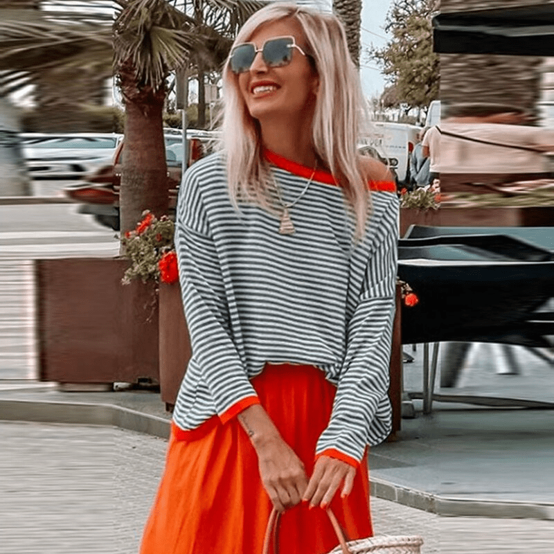 Blau-gestreifter Pullover mit orangefarbenem Rand, modisch und lässig, ideal für den Herbst. Perfekt kombiniert mit einem roten Rock.